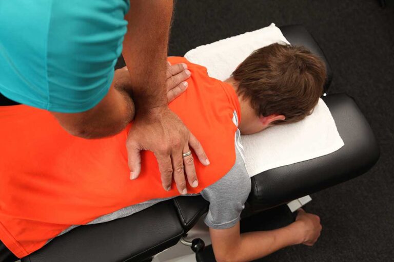 A pregnant person using a supportive pillow and gentle stretching techniques to ease back discomfort at home.